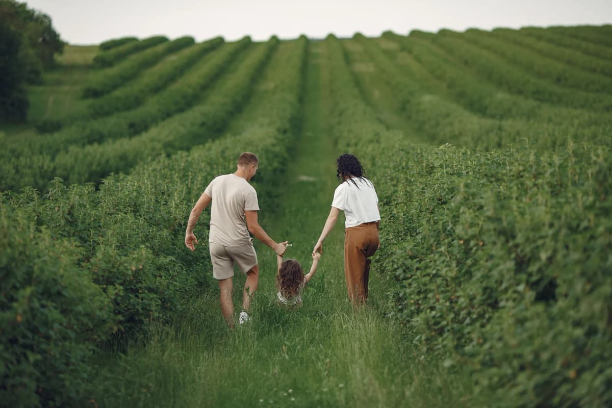 Happy family walking together through a lush green field enjoying nature and togetherness.